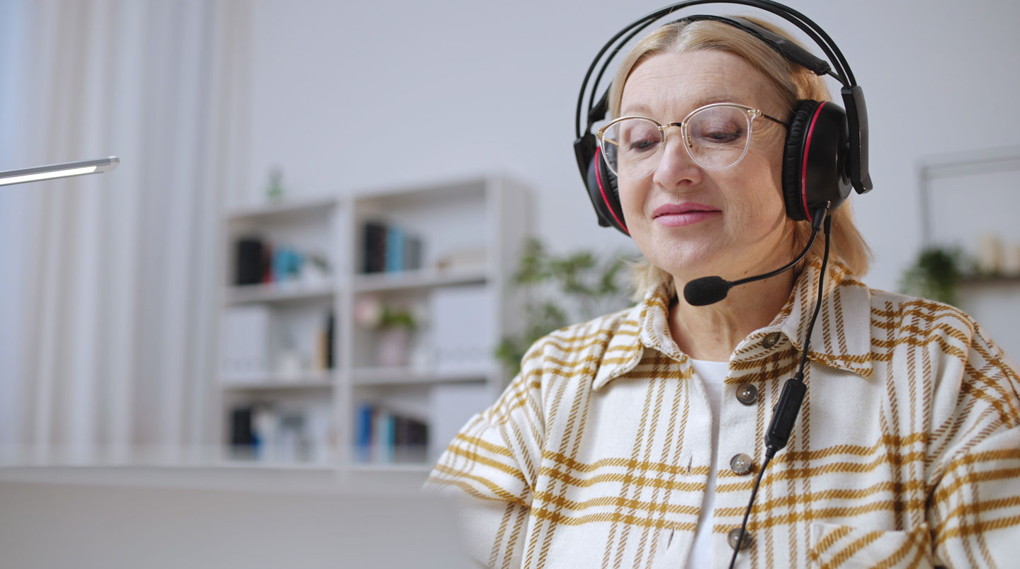 Opératrice de plateforme de téléassistance à son poste de travail avec casque et écrans affichant interfaces de gestion des appels d'urgence